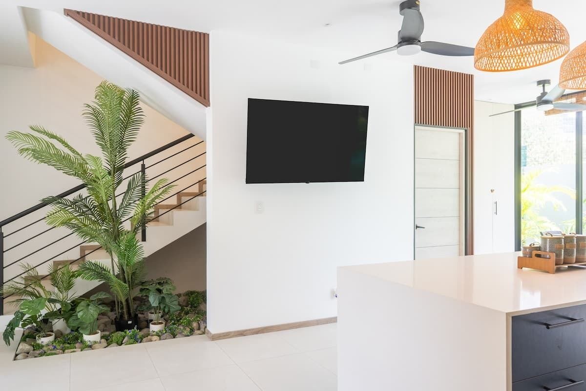 Un interior moderno con una escalera, un televisor de pantalla plana y un ventilador de techo.