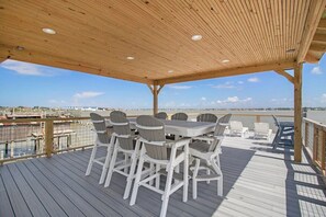 Terraza techada al aire libre con mesa y sillas, con vista al frente del agua.