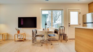 Une cuisine moderne avec un coin repas, un téléviseur à écran plat fixé au mur et une grande fenêtre offrant une vue sur l’extérieur.