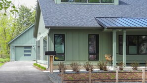 Un bâtiment à deux étages, à l’extérieur verdoyant, doté d’un porche abrité et d’une allée menant à un garage.