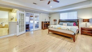 A spacious bedroom with a large bed, a ceiling fan, and a sliding glass door leading to a bathroom. - Work & Unwind, Stylish Sunnyvale Retreat! (Sunnyvale)