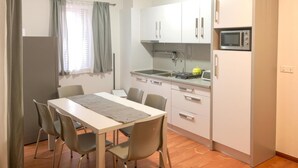 A compact kitchen with a dining table and chairs, a microwave, and a sink.
