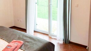 A room with a bed, a red towel, and a sliding glass door leading to a patio.