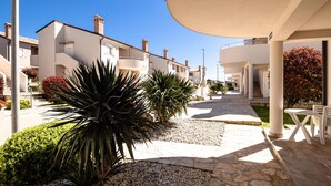 A residential street with modern houses, a paved walkway, and outdoor seating. - Beautiful apartment in Medulin (Medulin)