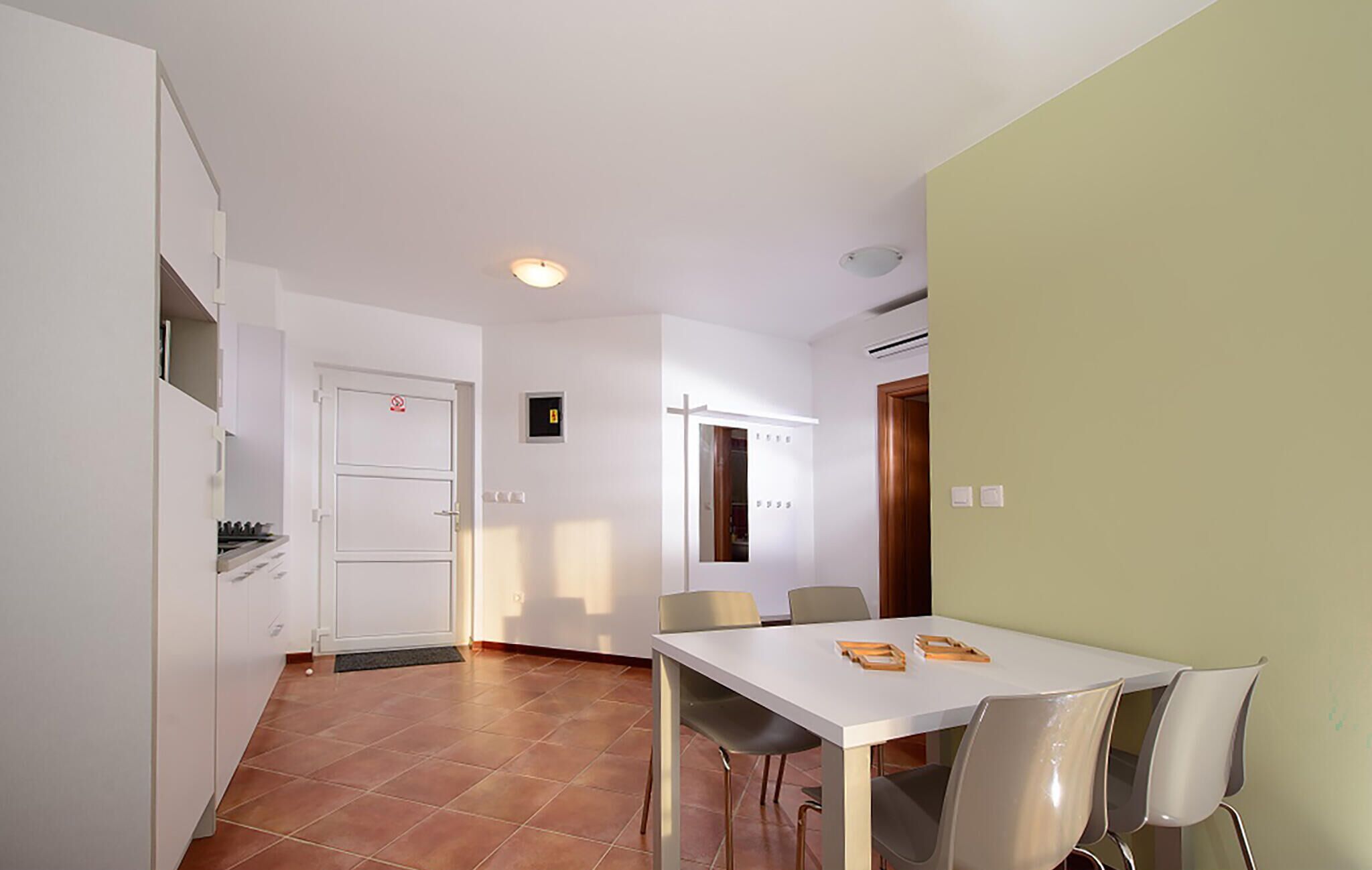Eine moderne Küche mit weißen Schränken, einem Side-by-Side-Kühlschrank und einem Essbereich mit einem weißen Tisch und vier Stühlen.
