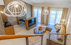 A modern living room with a flat-screen TV, a sofa, a coffee table, and a dining area with chairs. - Beautiful apartment in Medulin (Medulin)