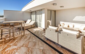 En moderne balkon med spisebord, loungesæde og sofa.