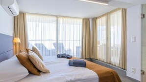 Camera d'albergo con un letto, tende, una lampada e vista sulla città.