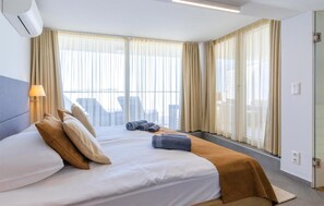 A hotel room with a bed, curtains, a lamp, and a view of the city. - 1 bedroom stunning apartment in Medulin (Medulin)