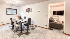 Ein Essbereich mit Marmorboden, einem Tisch mit Stühlen und einem Fernseher im angrenzenden Zimmer.