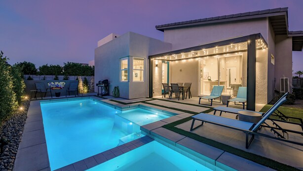 A modern outdoor pool area with a patio, lounge chairs, and a covered seating area. - Brand New! Chic, Gated & Safe. Family & Pet Friendly, Sleeps 9 with Rec. Room… (Indio)