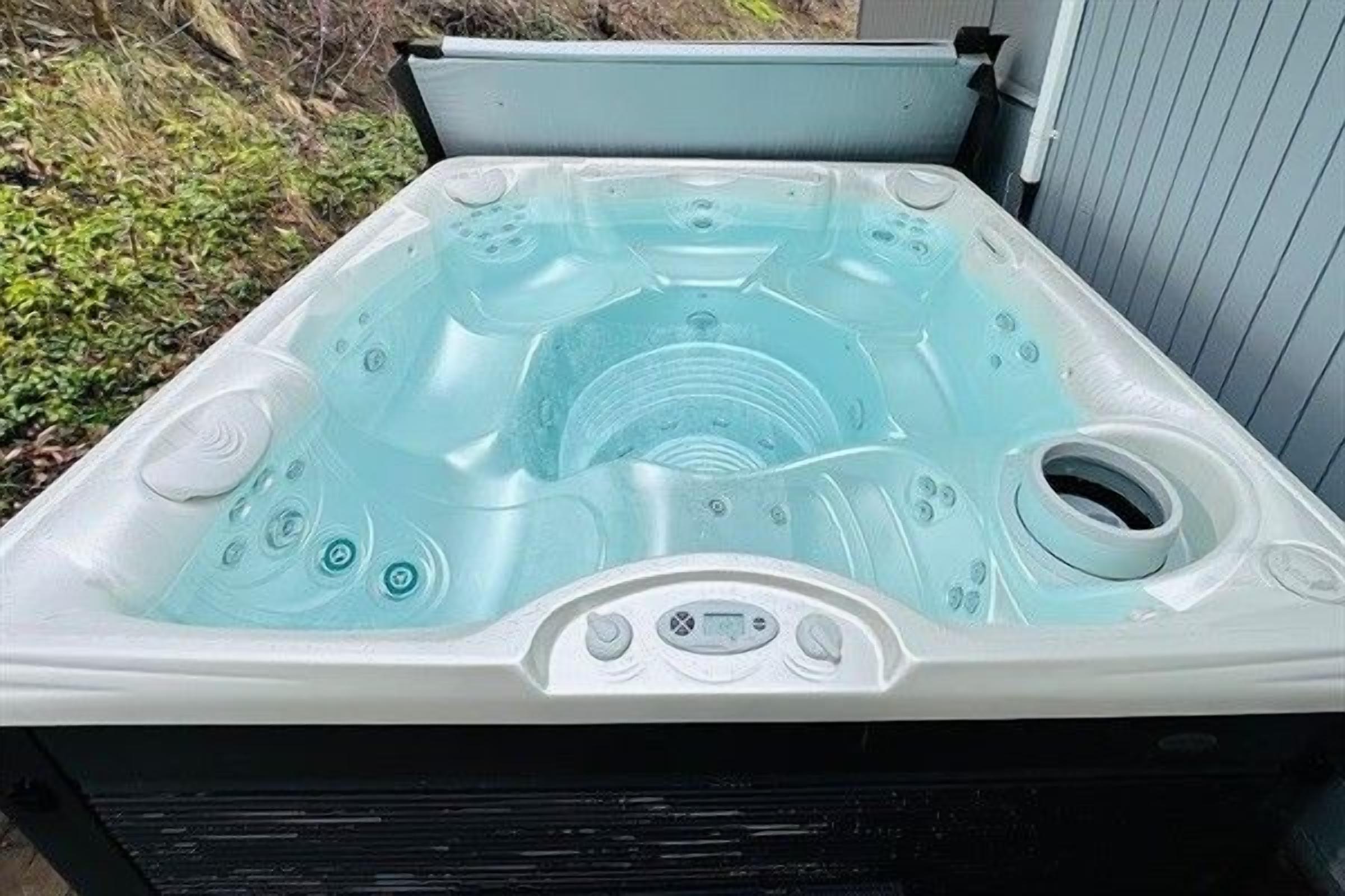 A hot tub with multiple jets and a control panel, set outdoors.