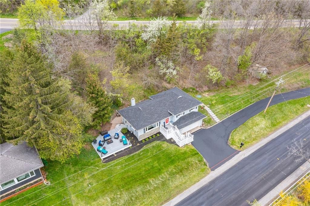 A two-story house with a covered patio and a driveway leading to a road.
