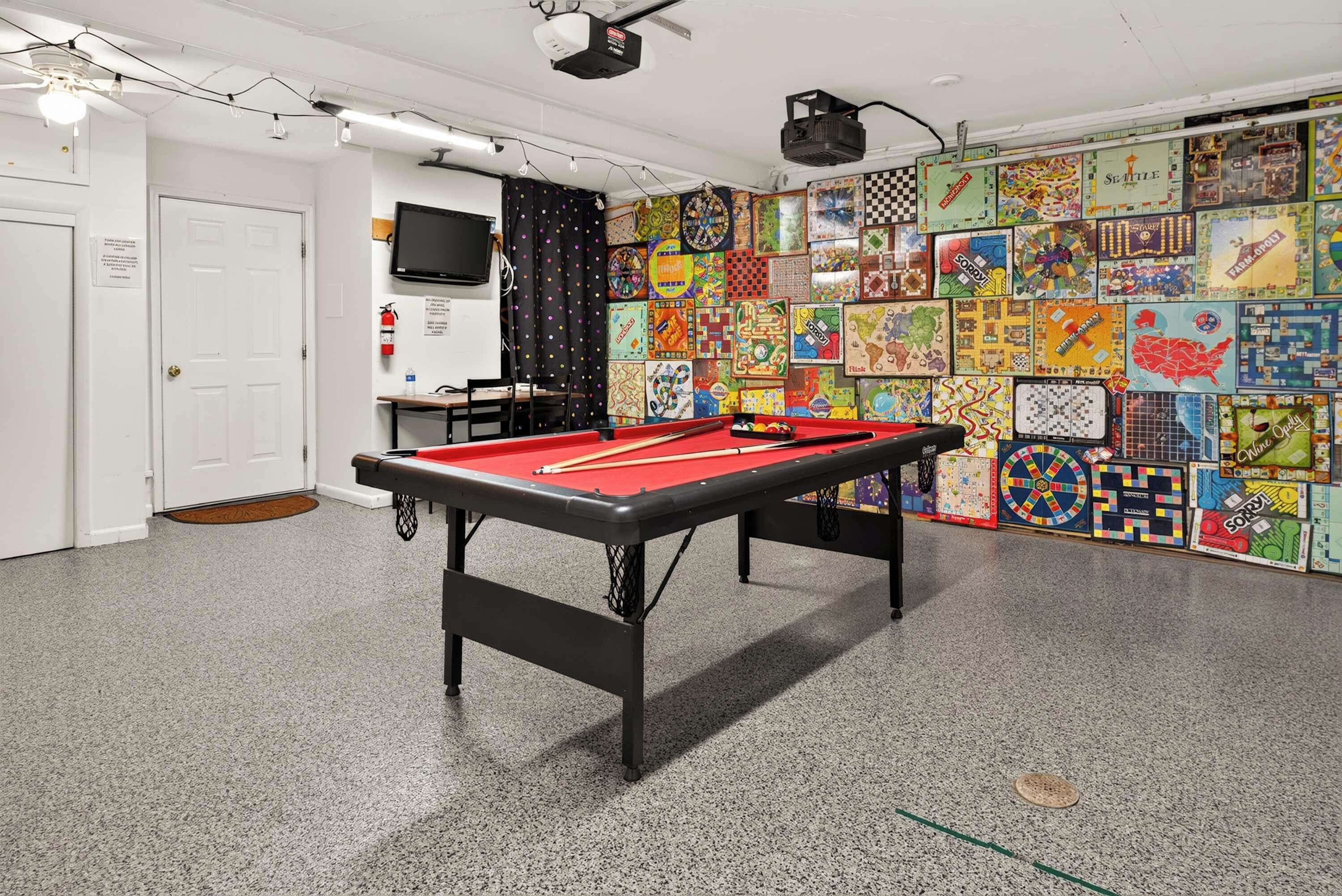 Een pooltafel in een ruimte met een wand vol verschillende gezelschapsspellen.