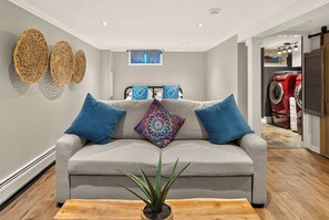 A modern living room with a grey sofa, blue cushions, and a wooden coffee table with a plant. - Canandaigua Lake Overlook (Canandaigua)