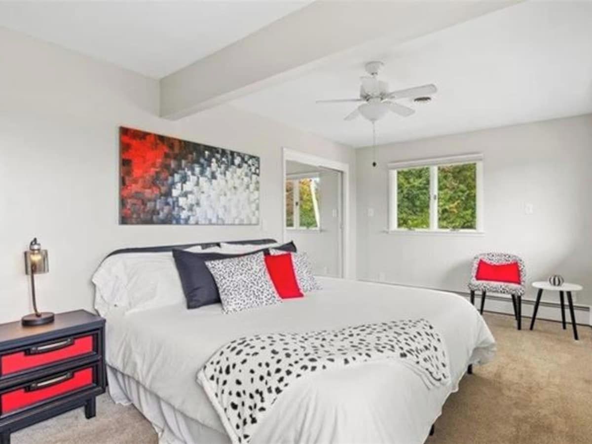 Quarto com cama, mesa de cabeceira, cadeira, janela e ventilador de teto.