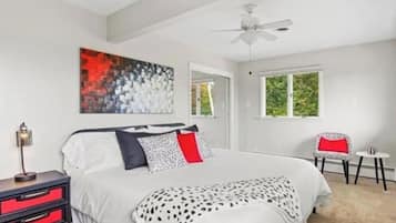 Quarto com cama, mesa de cabeceira, cadeira, janela e ventilador de teto.