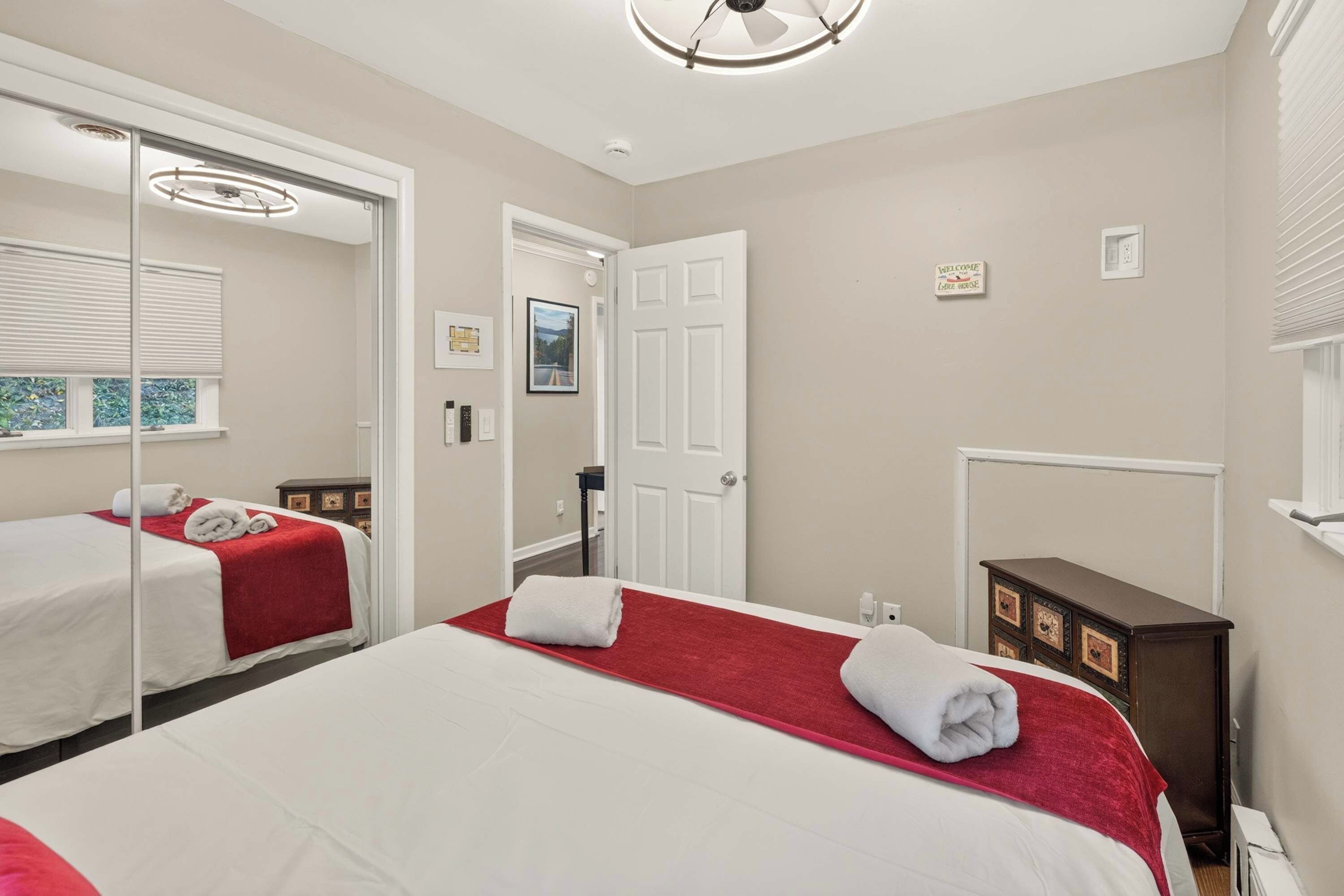 A hotel room with two beds, a large mirror, a wardrobe, and a door leading to another room.