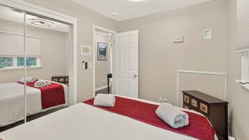 A hotel room with two beds, a large mirror, a wardrobe, and a door leading to another room.
