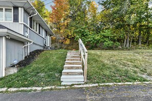 A residential property with a front yard, a wooden staircase leading to the entrance, and a house with a grey exterior. - Canandaigua Lake Overlook (Canandaigua)