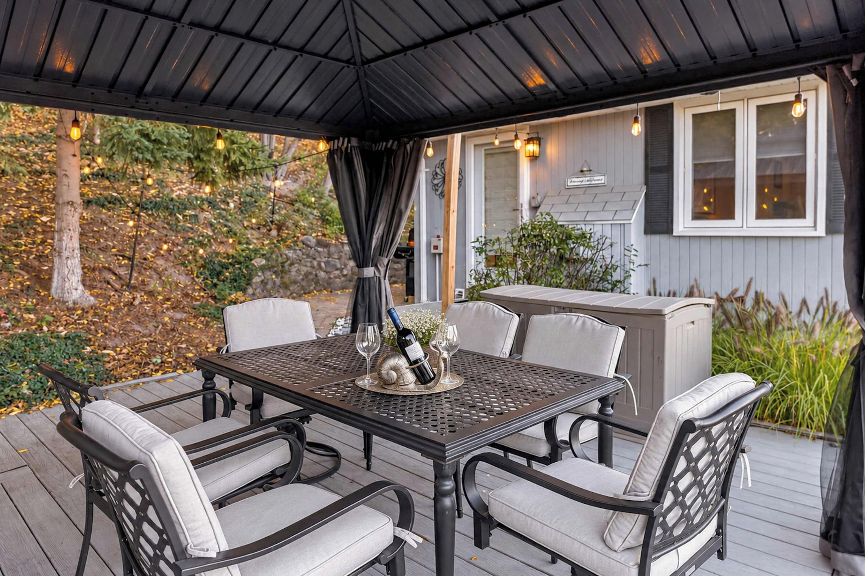 A covered outdoor patio with a table set for dining, surrounded by chairs.