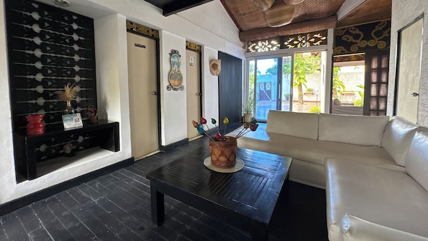 A modern interior with a black coffee table, white sofa, and a decorative wall with a black and gold pattern. - Auaecoco Hotel (Cartagena)