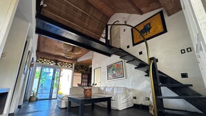 A spacious living area with a staircase, a white sofa, a coffee table, and a painting on the wall. - Auaecoco Hotel (Cartagena)