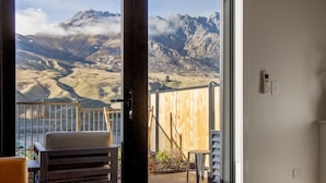 Una habitació amb vistes a les muntanyes, una tanca de fusta, una cadira i una taula petita.