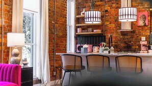 A modern kitchen with a brick wall, two pendant lights, and a bar area with stools.