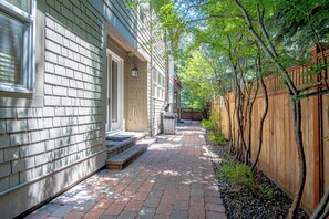 A brick pathway leading to a house with a wooden fence and trees. - Cozy Ketchum Retreat - Pet Friendly! (Ketchum)