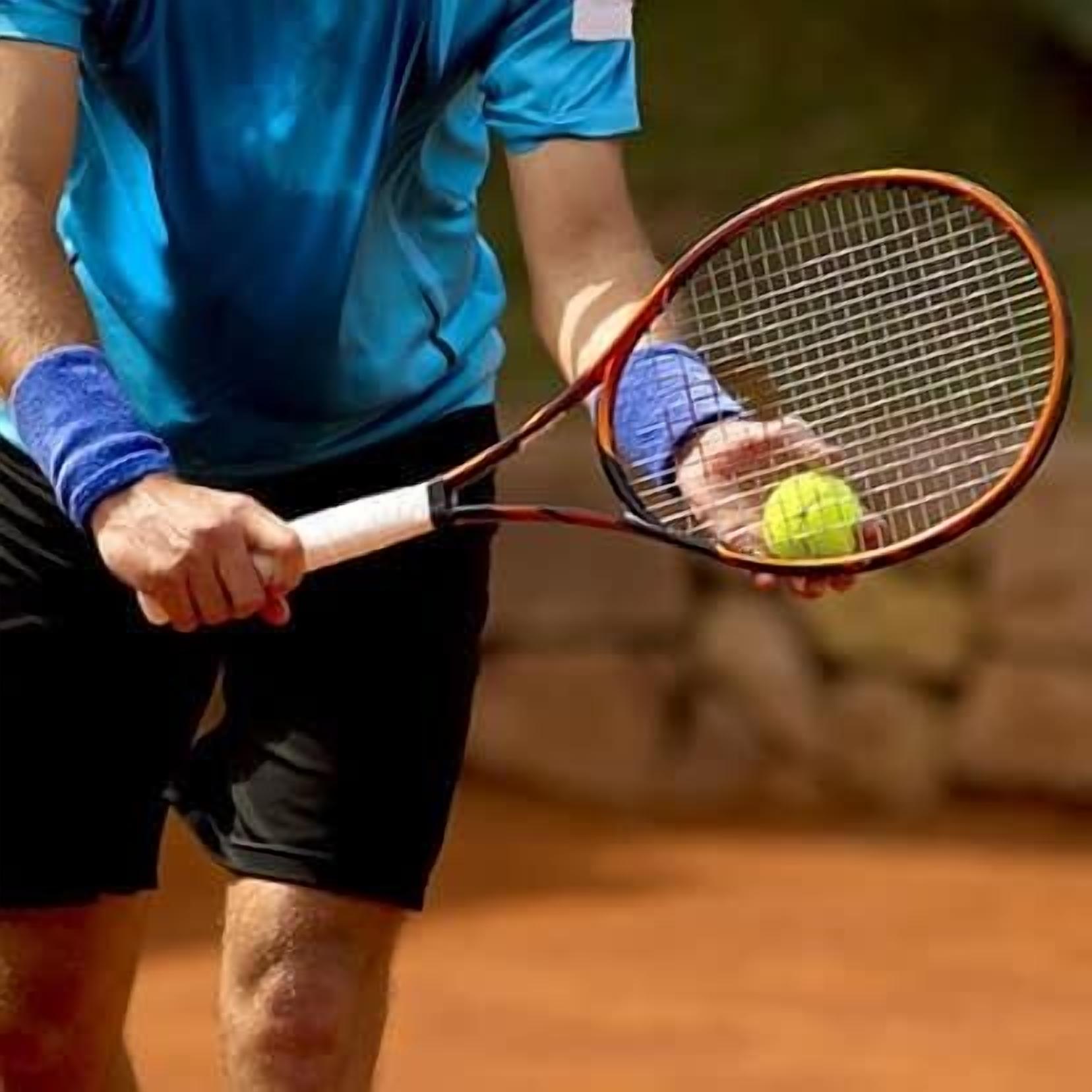 A person holding a tennis racket and a tennis ball on a clay court.