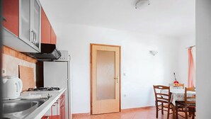 Una cucina compatta con fornello, lavandino e zona pranzo con sedie e tavolo.