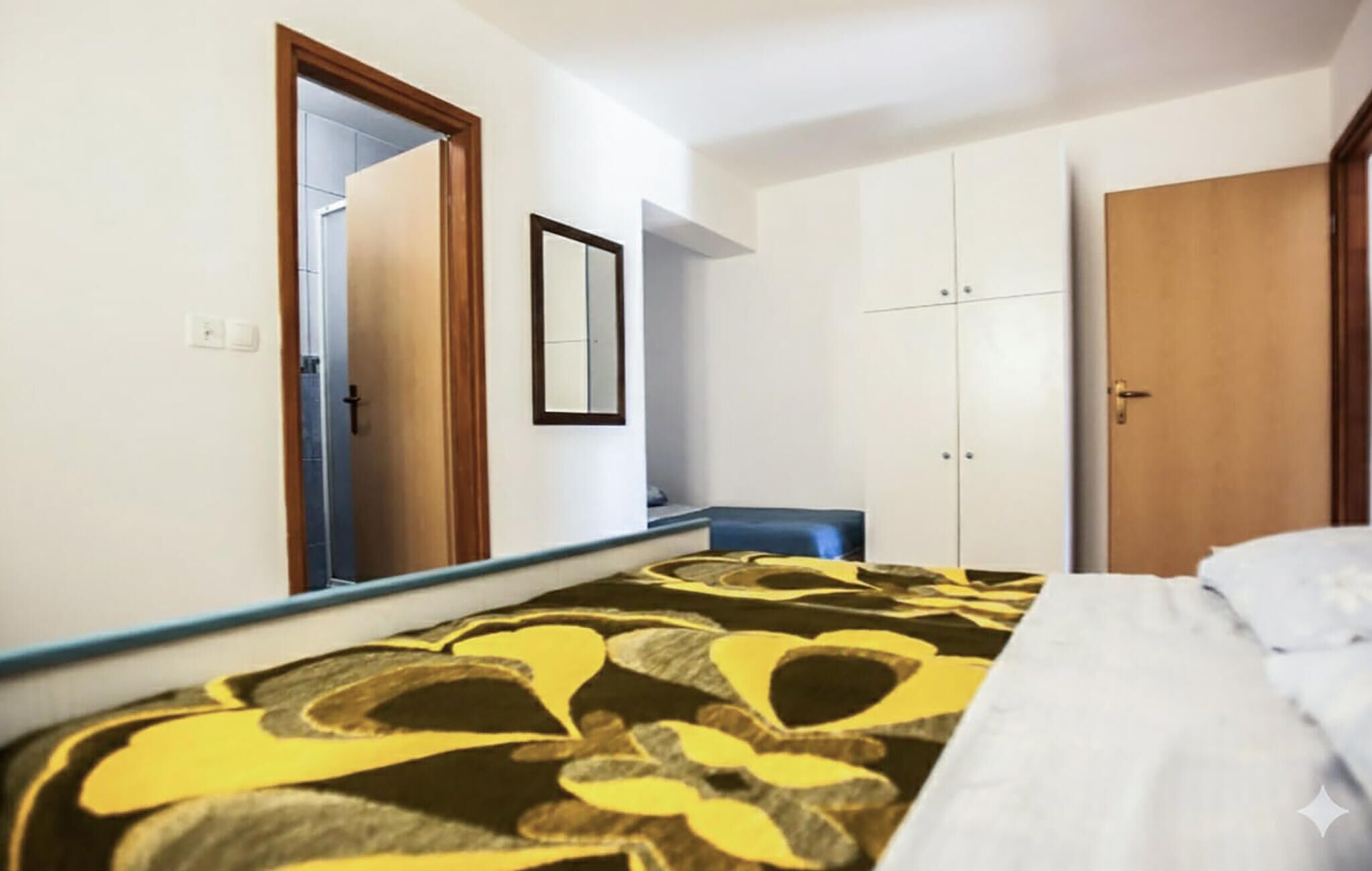A bedroom with a bed, a wardrobe, a mirror, and a door.