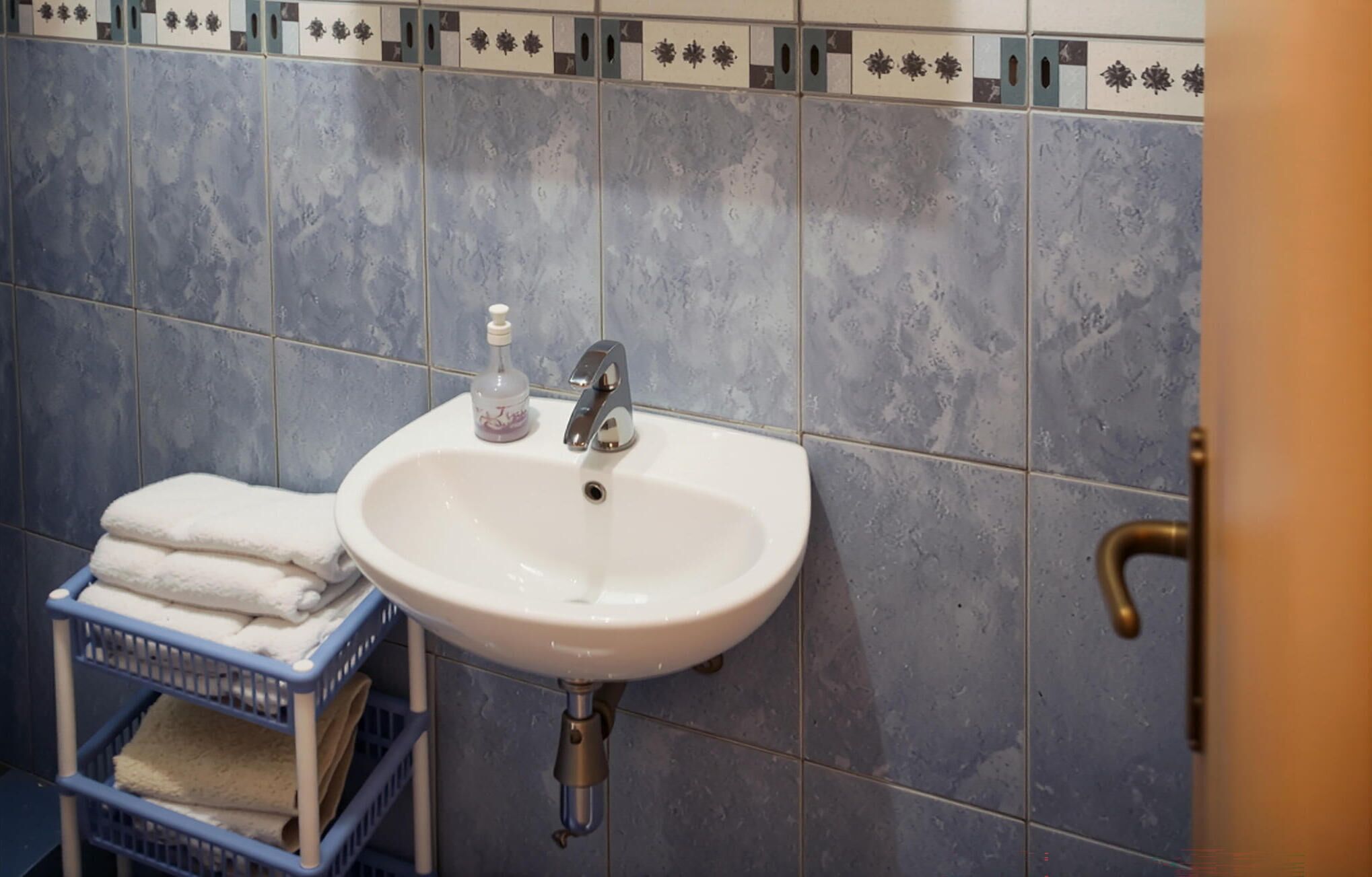 Une salle de bain avec un lavabo blanc, un distributeur de savon et un porte-serviettes avec des serviettes pliées.