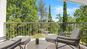 A balcony with wicker furniture and a small table, overlooking a lush green landscape. - Luxurious home in Opric with sauna (Opric)