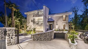 A modern two-story villa with a stone facade, a garage, and a landscaped garden. - Luxurious home in Opric with sauna (Opric)