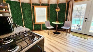 Una cocina pequeña con estufa, ventana y dos sillas.