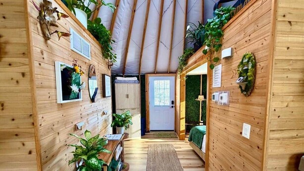 Un interior de madera con techo alto, una puerta central y plantas en macetas.