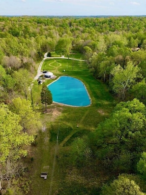 Vista aérea de una propiedad con una amplia piscina azul rodeada de exuberante vegetación y un sendero sinuoso.