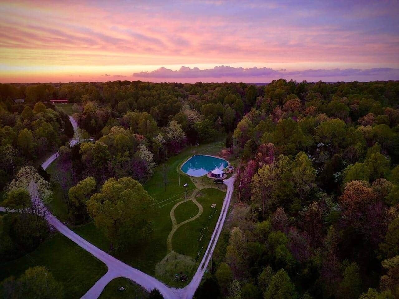 An aerial view of a property with a swimming pool, a house, and a well-maintained lawn.