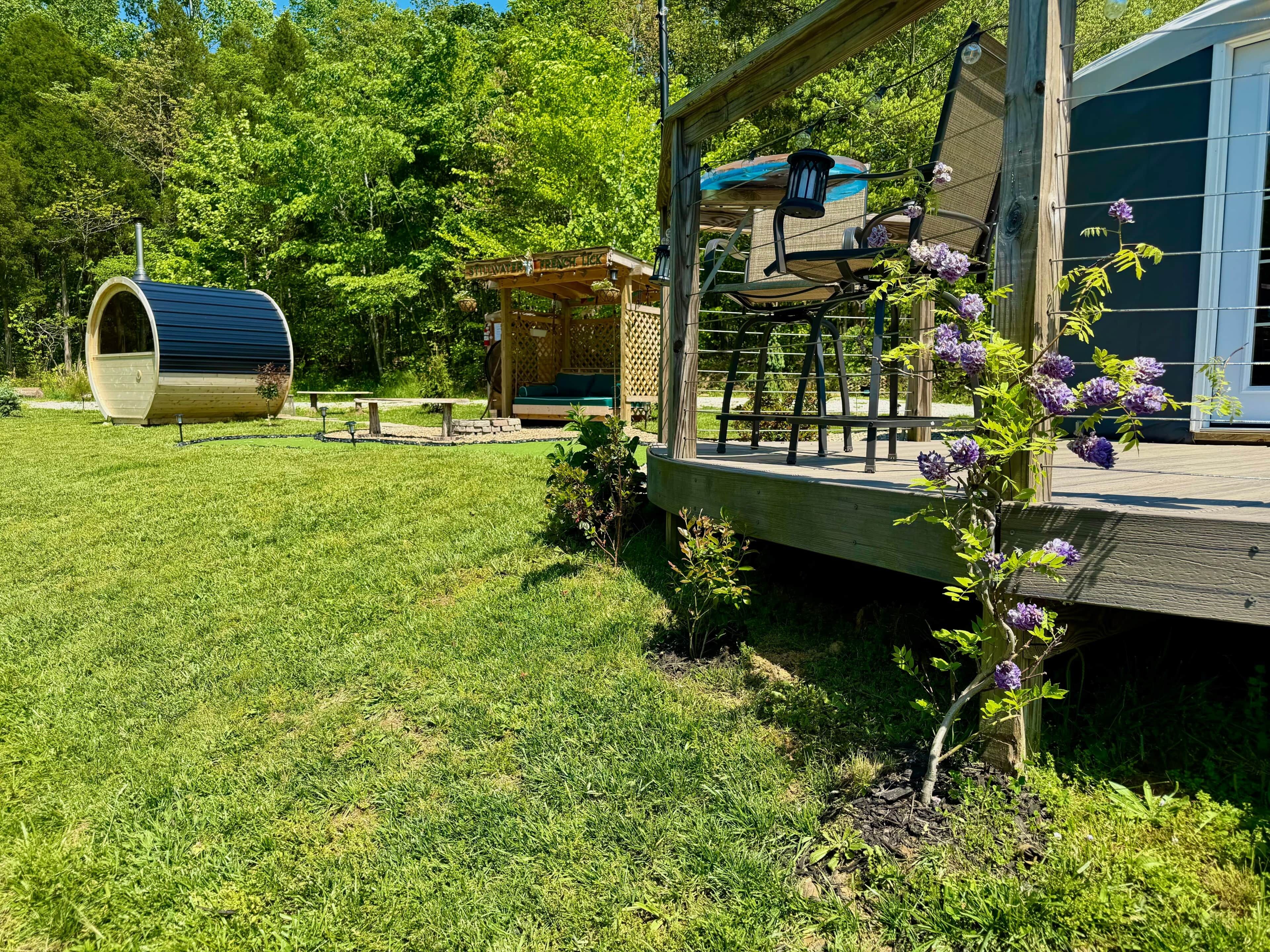 Um deck de madeira com pérgola, baloiço e área de estar coberta.