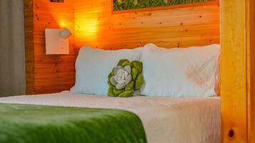 A wooden-paneled room with a bed, a wall-mounted light, and a decorative plant.