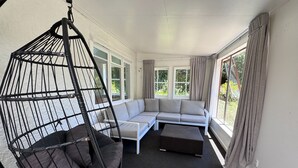 Un salon moderne avec un fauteuil suspendu, un canapé d’angle et une table basse.