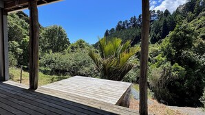 Une terrasse en bois offrant une vue sur une forêt luxuriante et des collines.