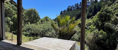 Una terraza de madera con vistas a un bosque frondoso y colinas.