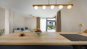 A modern kitchen with a wooden countertop, a bowl of fruit, and a black induction cooktop. - Lovely home in Rogoznica (Rogoznica)