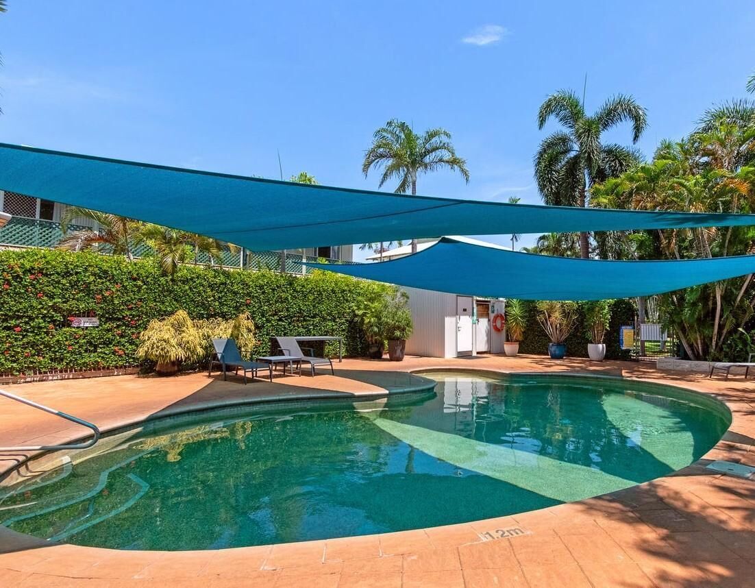 Secluded poolside retreat with vibrant shade sails and lush greenery