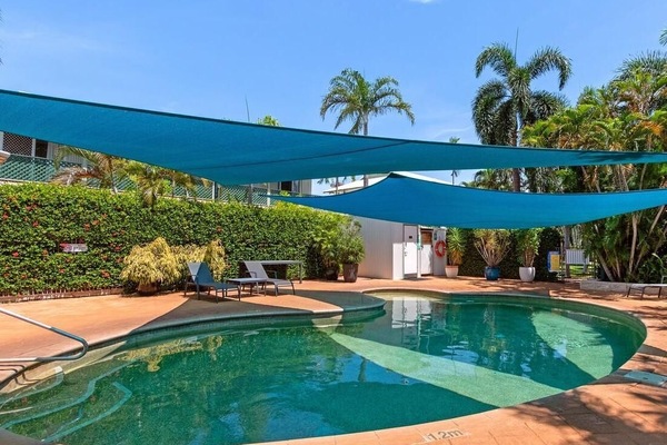 Secluded poolside retreat with vibrant shade sails and lush greenery