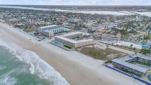 Una vista aerea di una città costiera con una spiaggia, un porto turistico e un ponte.