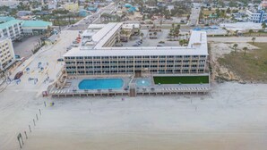 Un hotel con una grande piscina, diversi piani e vista sulla spiaggia.
